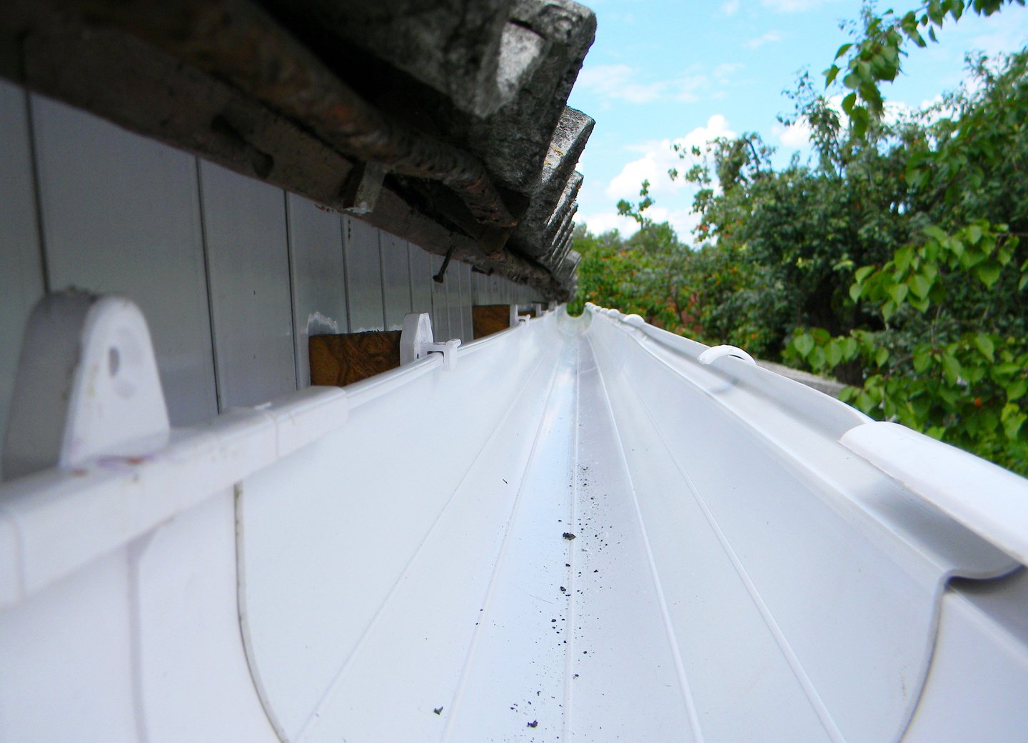 Rain gutter view. Install plastic roof gutter. Guttering repair.